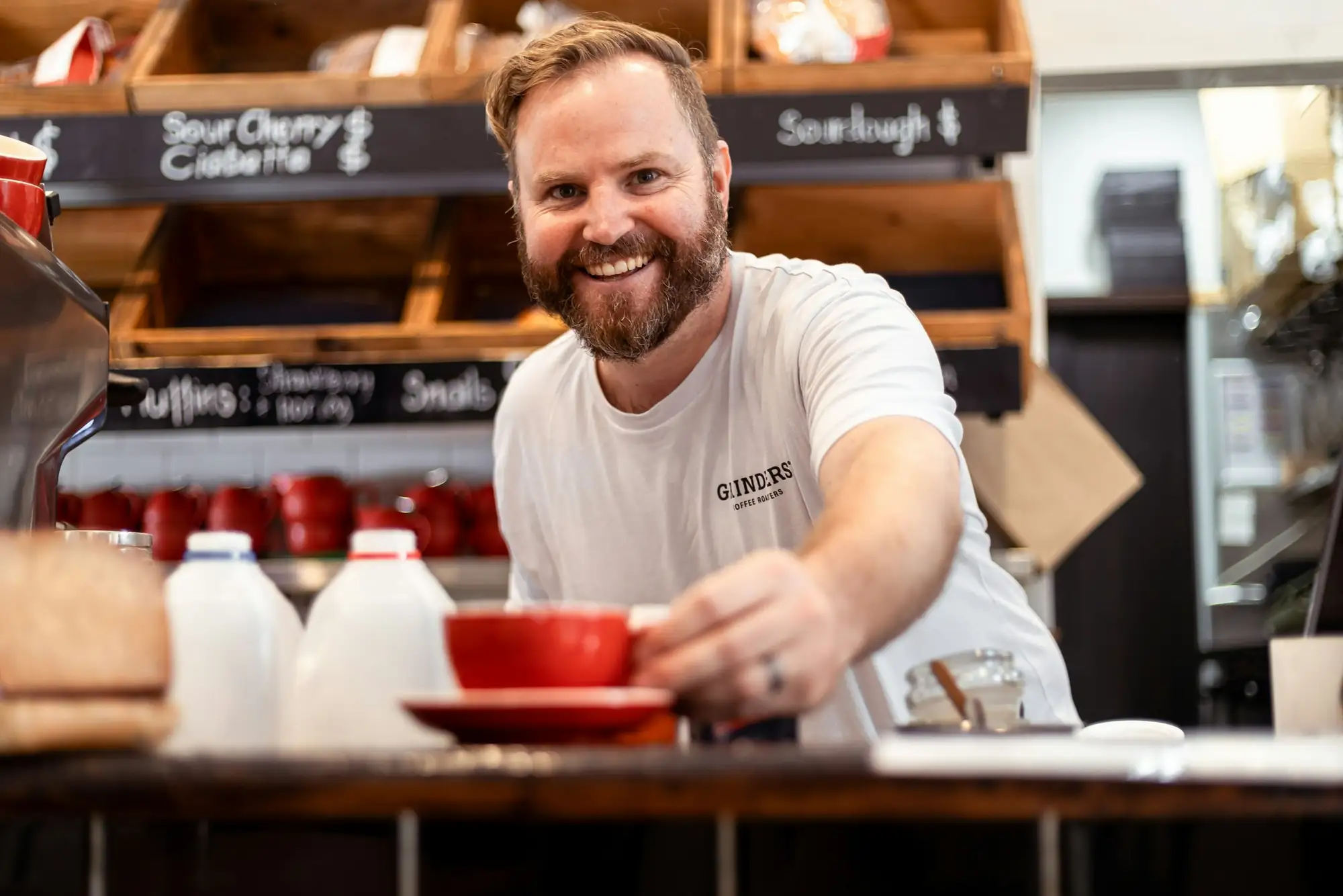 Smiling café owner serving a coffee across the counter