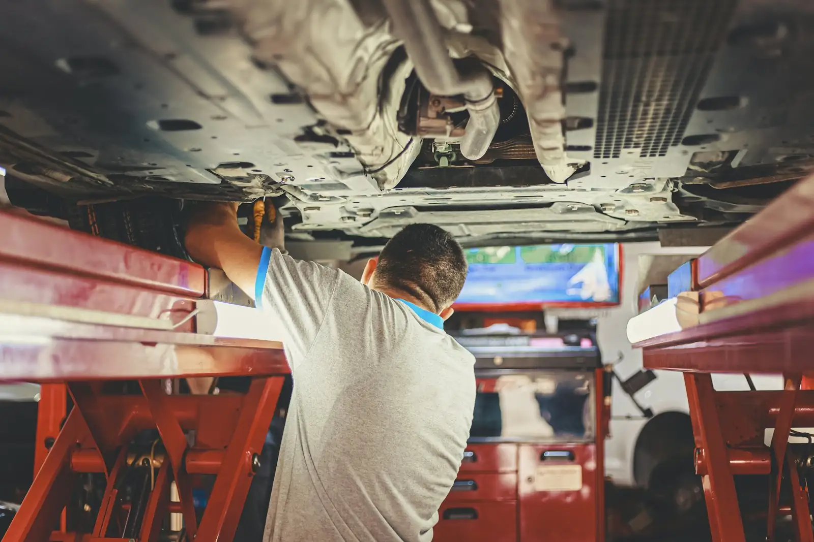 Mechanic working under a vehicle on a hoist
