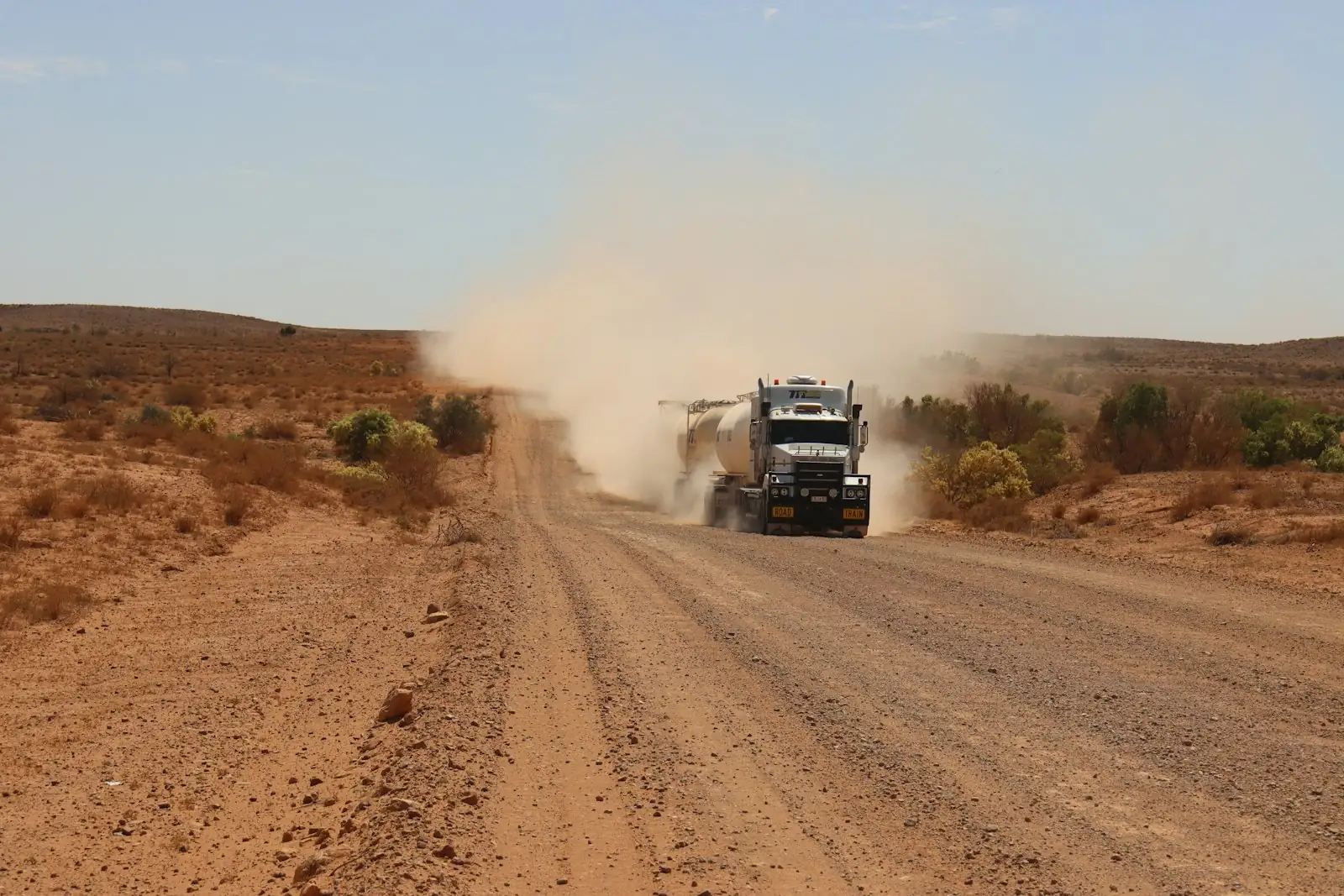 Truck kicking up dust on a red outback road